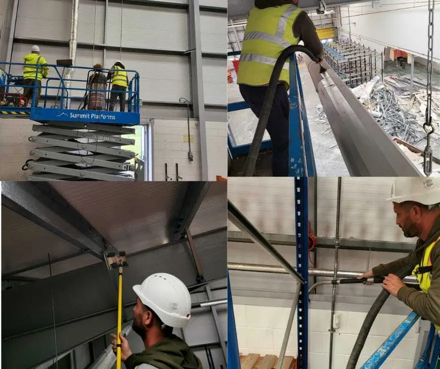 Echipă NCC Services curățând structura metalică a unei hale de pe platformă ridicătoare