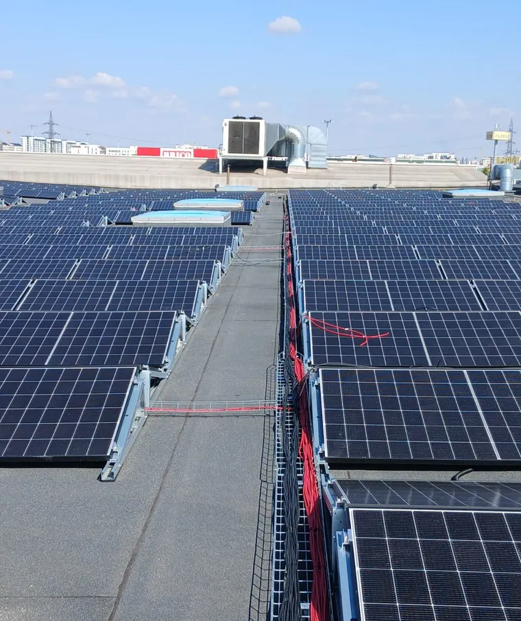 Rânduri de panouri fotovoltaice pe un acoperiș industrial, văzute de aproape